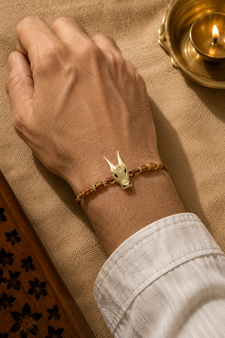 Nandi brass rakhi with rice, haldi & kum kum dibbi gift pack.